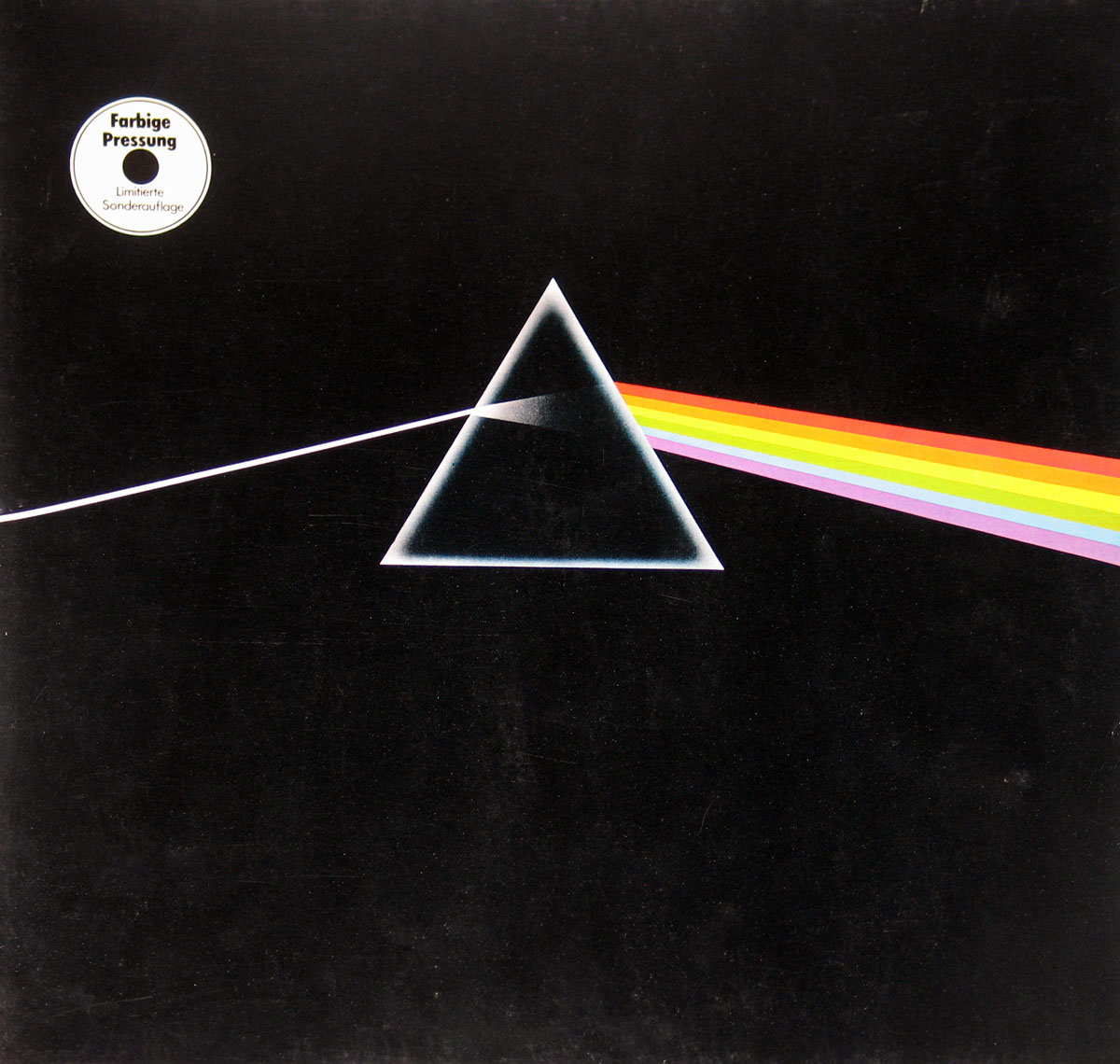 ‘Limited-edition “Sonderauflage” album cover of Pink Floyd’s The Dark Side of the Moon, featuring a black background with a white light beam entering a central prism, refracting into a rainbow of colors extending to the right. A circular label in the top left corner reads “Farbige Pressung Limitierte Sonderauflage,” signifying a rare colored vinyl pressing.’